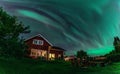 Panorama of dancing Northern lights Aurora borealis in autumn over wooden house, apple tree, tree benches in backyard. Umea town,