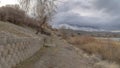 Panorama Dirt road along the retaining wall of slope overlooking lake and snowy mountain