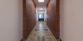 panorama in empty long corridor with red brick walls and doors in interior of modern office