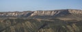 Panorama in the evening in the mountains of the Caucasus on a steep rocky slope of a table mountain and wooded hills with trees Royalty Free Stock Photo