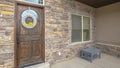 Panorama Facade of home with porch stone brick wall brown door and transom window