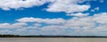 panorama of a fluffy cloud filled blue sky over a vast lake in a national park area on a summer day in rural Victoria,