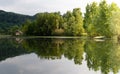 Panorama of the forest reflected in the lake water. On the shore you can see a hut and a boat. View from the shore of Lago di Lago