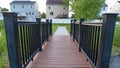 Panorama frame Close up of bridge with brown wood deck and black guardrail over a grassy pond