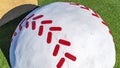 Panorama frame Close up of a huge white and red baseball decoration against a vibrant green lawn