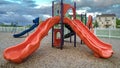 Panorama frame Colorful slides and swings on a neighborhood playground under cloudy blue sky Royalty Free Stock Photo