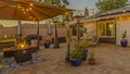 Panorama frame Cozy stone patio with string of lights over a covered seating and dining area