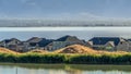 Panorama frame Homes amid a shiny lake with view of distant mountain towering over the valley Royalty Free Stock Photo