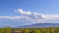 Panorama frame Panoramic view of rooftops and lush trees under blue sky with puffy clouds Royalty Free Stock Photo