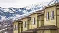 Panorama frame Row of cream colored homes with snow covered mountain and cloudy sky background Royalty Free Stock Photo