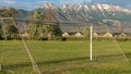 Panorama frame Soccer net on a sports field with snow capped mountain and cloudy sky background