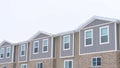 Panorama frame Upper storey of townhomes with snowy pitched roofs on a cold winter day