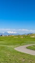 Panorama frame Vast grassy field with a curving paved road and houses beyond the slopes Royalty Free Stock Photo