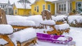 Panorama Frosted shrubbery behind wooden chairs and purple sled in Daybreak Utah