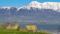 Panorama Grassy terrain with an empty outdoor bench facing a lake and snowy mountain