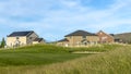 Panorama Grassy terrain and houses under blue sky with white clouds on a sunny day