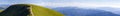 Panorama of green hills in summer mountains with gravel road for Royalty Free Stock Photo