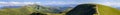 Panorama of green hills in summer mountains with gravel road for Royalty Free Stock Photo