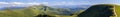 Panorama of green hills in summer mountains with gravel road for Royalty Free Stock Photo