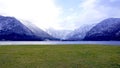 Panorama of Hallstatt lake and green grass field outdoor with snow mountain in Austria in Austrian alps