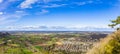 Panorama on hilly area with forests, fields, houses and highways in sunlight against a cloudy sky Royalty Free Stock Photo