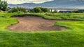 Panorama Hole filled with sand amid a grassy terrain against home lake mountain and sky Royalty Free Stock Photo