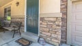 Panorama Home with green door yard windows and porch bench against stone brick wall Royalty Free Stock Photo