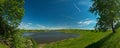 panorama, horizontal view of bay. Great blue lake and green field Royalty Free Stock Photo