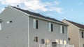 Panorama A house with gray horizontal wood siding and stairs that leads to the balcony