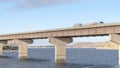 Panorama Huge truck travelling on a bridge that crosses a blue lake under cloudy sky