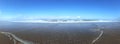 Panorama image of a beach or bay on the atlantic ocean with sand, breaking waves and a blue sky with clouds on a sunny day