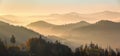 Panorama with interesting sunrise enlightens surroundings. Landscape with beautiful mountains, forests covered with morning fog.