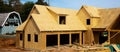 Panorama L shaped wooden house with gabled dormer roof under construction, oriented strand board OSB plywood sheeting envelope in