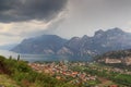 Panorama of Lake Garda, lakeside village Torbole and mountains with dark storm clouds, Italy