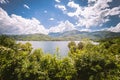 Panorama of a lake with green vegetation around. Natural basin with forest and mountains. Royalty Free Stock Photo