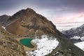 Panorama of a landscape with a green lake high in the mountains with white snow and a climbing camp