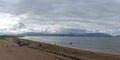 Panorama landscape of Inch Strand in Dingle Bay with many cars and beachgoers on a cloudy summer day