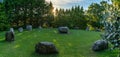 Panorama landscape of the Kenmare Standing Stones and Wishing Tree in warm evening light with a sunburst