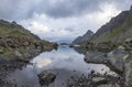 Panorama landscape with a lake in the mountains, huge rocks and stones on the coast and reflection of clouds Royalty Free Stock Photo