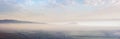 panorama of a landscape with rural fields at the foot of a mountain range in morning mist