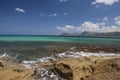Panorama landscape scenic view of isolated deserted yellow rocky beach with blue turquoise sea water and sky with white clouds and