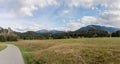 Panorama landscape view of green pastures and forest in fall colors with snow-capped mountains behind in the Alps of Switzerland a Royalty Free Stock Photo