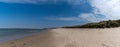 Panorama landscape with wooden stairs leading over tall grassy sand dunes onto an empty picturesque golden sand beach Royalty Free Stock Photo