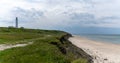 Panorama of the lighthouse and grassy sand dunes above the white sand beach at Hirtshals in northern Denmark