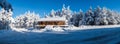 Panorama with a log cabin covered in a snowy forest