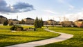 Panorama Lush field with a curving pathway that leads to the houses in the distance