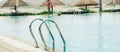 Panorama luxury ocean view tropical resort swimming pool with stainless steel handrail, row of beach umbrella thatched with palm Royalty Free Stock Photo