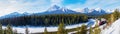 Panorama of Morant\'s Curve in Banff National Park as red cargo train passes through in Winter