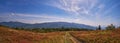 Panorama of a mountain meadow on an autumn sunny day with a dirt road Royalty Free Stock Photo