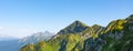 Panorama of a mountain range with shady gorges and alpine meadows on the slopes, other mountains in the distance Royalty Free Stock Photo